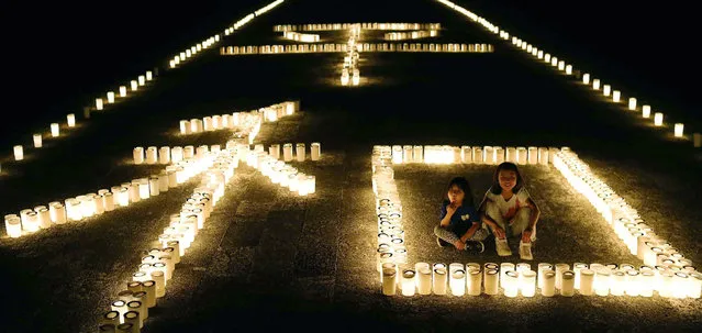 This photo taken on June 22, 2016 shows candles displaying the Chinese characters for “peace” in Okinawa on the eve of a ceremony marking the 71st anniversary of the end of the Battle of Okinawa. Japanese Prime Minister Shinzo Abe was expected to attend a ceremony on June 23 to mark the anniversary, after a massive protest against the heavy US military presence on the island over the weekend. (Photo by AFP Photo/JIJI Press)