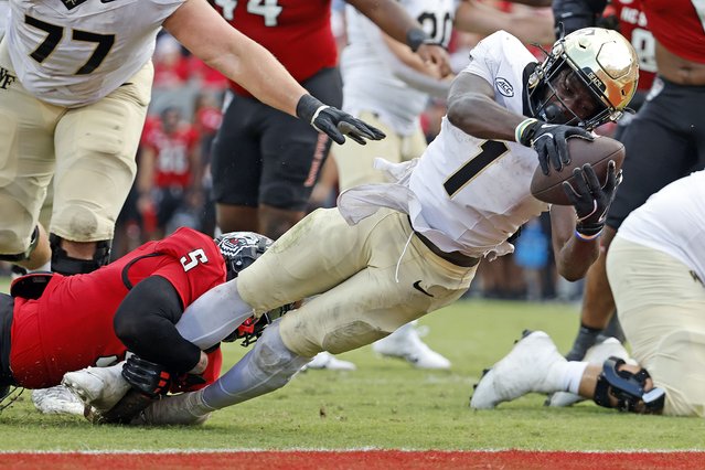 Wake Forest running back Demond Claiborne (1) stretches in the grasp of North Carolina State's DK Kaufman (5) during the second half of an NCAA college football game in Raleigh, N.C., Saturday, October 5, 2024. (Photo by Karl B DeBlaker/AP Photo)