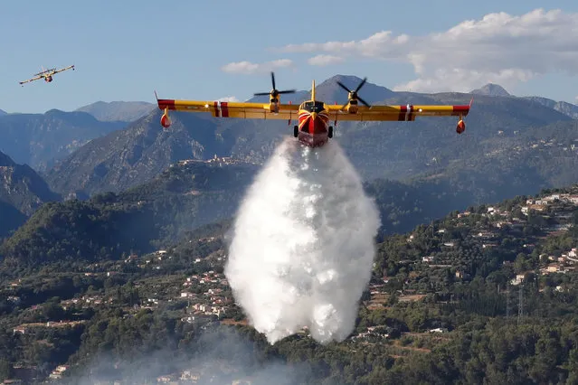 A Canadair firefighting aircraft drops water on a wildfire which burns a forest in Carros, near Nice, France, July 24, 2017. (Photo by Eric Gaillard/Reuters)