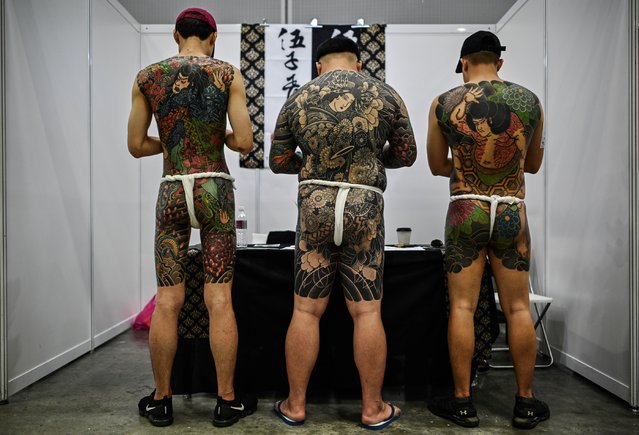 Three men display their tattoos during the International Malaysia Tattoo Expo in Kuala Lumpur on November 29, 2019. The international tattoo expo is held for the first ime in Kuala Lumpur celebrating that art of tattoo and gathering over a hundred tattoo artists from 40 countries. (Photo by Mohd Rasfan/AFP Photo)