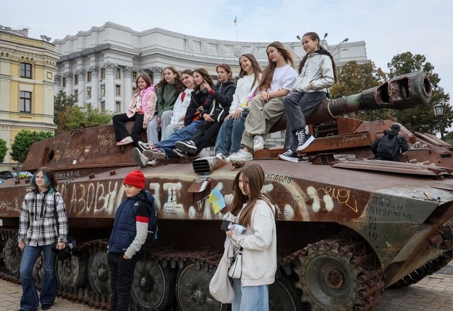 Youths pose for a picture atop a destroyed Russian self-propelled howitzer as they visit an exhibition displaying destroyed Russian military vehicles, amid Russia's invasion, in central Kyiv, Ukraine on October 3, 2024. (Photo by Gleb Garanich/Reuters)