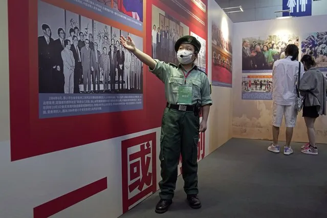A young volunteer shows the picture to visitors at an exhibition to celebrate the 25th anniversary of Hong Kong handover to China in Hong Kong, Friday, June 24, 2022. (Photo by Kin Cheung/AP Photo)