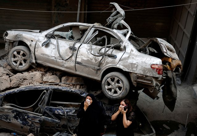 Women stand next to damaged vehicles at the site of an Israeli air strike, amid ongoing hostilities between Hezbollah and Israeli forces, in Beirut, Lebanon, on October 11, 2024. (Photo by Louisa Gouliamaki/Reuters)