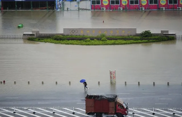A man holds an umbrella as he wades through a flooded street in Quanzhou, Fujian province, July 23, 2014. Typhoon Matmo hit Taiwan on Wednesday, bringing heavy rain and strong winds, shutting financial markets and schools. It passed the island and headed into China, downgraded from typhoon to tropical storm. (Photo by Reuters/Stringer)