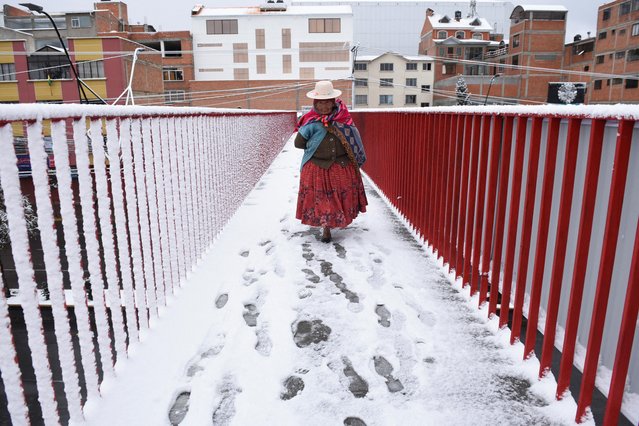 A woman crosses a pedestrian bridge after a heavy snowfall, in El Alto, Bolivia on August 13, 2023. (Photo by Claudia Morales/Reuters)