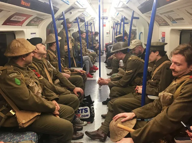 Men dressed as First World War soldiers mingle with regular commuters aboard an underground tube train in London, to mark 100-years since the start of the Battle of the Somme, early Friday July 1, 2016. London commuters were met by the eerie sight of people dressed as World War I soldiers as they made their way to work Friday, with the soldiers singing wartime songs or remaining silent, revealed later Friday as a Somme tribute, the work of Turner Prize-winning artist Jeremy Deller, National Theatre Director Rufus Norris and thousands of volunteers. (Photo by Sarah Perry/PA Wire via AP Photo)