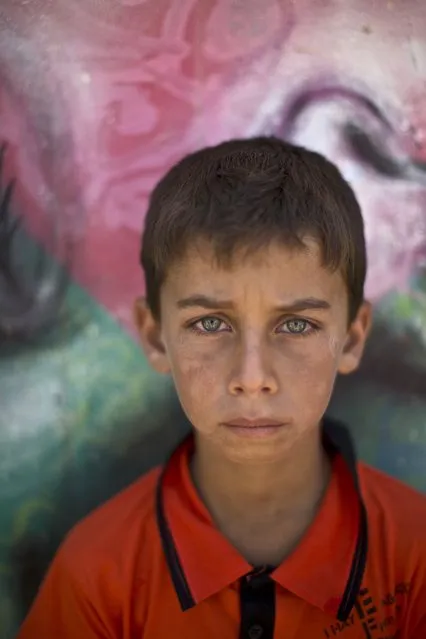 In this Tuesday, July 29, 2014 photo, Syrian refugee Mohammed, 12, poses for a picture at Zaatari refugee camp, near the Syrian border, in Mafraq, Jordan. Some children work in Zaatari, while the lucky attend school at the camp. (Photo by Muhammed Muheisen/AP Photo)