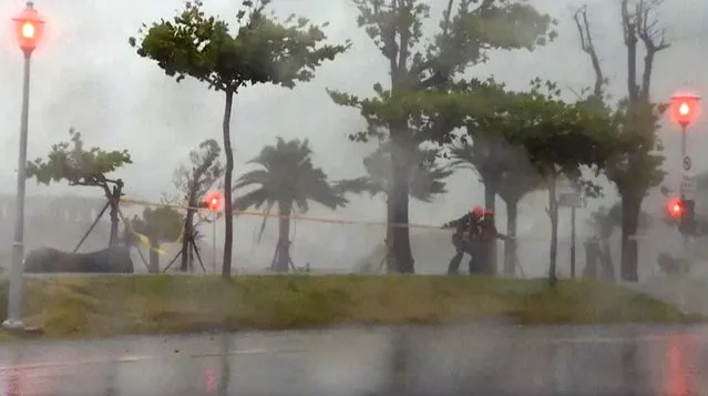 In this image made from video, two people brace themselves in strong winds from Typhoon Nepartak in Taitung, south eastern Taiwan, Friday, July 8, 2016. (Photo by EBC via AP Video)