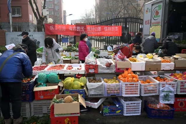 Residents wearing face masks buy food at a grocery stall that is set up outside a residential compound in Beijing, China on February 21, 2020. The banner reads, “Protection against epidemic, make purchases orderly, wear face masks, keep a distance”. (Photo by Tingshu Wang/Reuters)