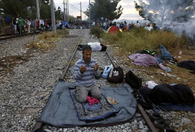 A Syrian refugee prays on a rail track at the Greek-Macedonian border, near the village of Idomeni, August 22, 2015. Crowds of migrants and refugees were building on Greece's border with Macedonia on Saturday after a cold, wet night spent in the open, their entry slowly rationed by Macedonian police and soldiers. (Photo by Yannis Behrakis/Reuters)