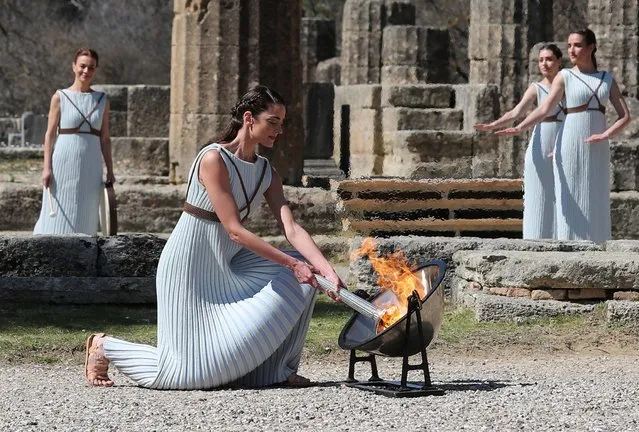 Greek actress Xanthi Georgiou, playing the role of High Priestess, takes the flame from the parabolic mirror during the Olympic flame lighting ceremony for the Tokyo 2020 Summer Olympics in Olympia, Greece on March 12, 2020. Greek Olympic officials are holding a pared-down flame-lighting ceremony for the Tokyo Games due to concerns over the spread of the coronavirus. Both Wednesday's dress rehearsal and Thursday's lighting ceremony are closed to the public, while organizers have slashed the number of officials from the International Olympic Committee and the Tokyo Organizing Committee, as well as journalists at the flame-lighting. (Photo by Alkis Konstantinidis/Reuters)