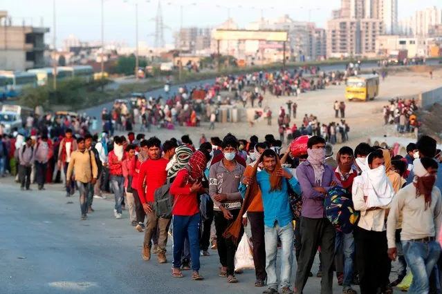 Migrant workers walk towards a bus station along a highway with their families as they return to their villages in Ghaziabad, on the outskirts of New Delhi, March 29, 2020. (Photo by Adnan Abidi/Reuters)