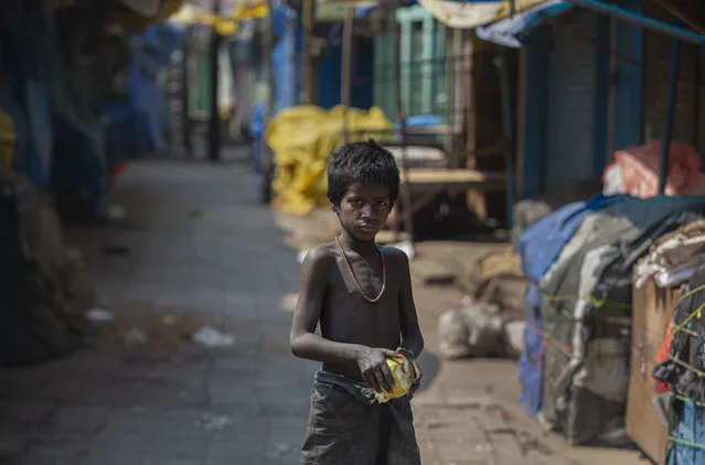 A homeless boy collects rotten fruits from a deserted fruit market during lockdown in Gauhati, India, Wednesday, March 25, 2020. The world's largest democracy went under the world's biggest lockdown Wednesday, with India's 1.3 billion people ordered to stay home in a bid to stop the coronavirus pandemic from spreading and overwhelming its fragile health care system as it has done elsewhere. For most people, the new coronavirus causes mild or moderate symptoms, such as fever and cough that clear up in two to three weeks. For some, especially older adults and people with existing health problems, it can cause more severe illness, including pneumonia and death. (Photo by Anupam Nath/AP Photo)