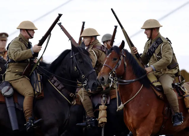 Heavy goods vehicle driver Philip Francis (3rd L), portraying a private from the 16th Lancers, rides his horse Cassius as he participates in a mock battle illustrating the First World War at the Colchester Military Tournament in Colchester, eastern England, July 6, 2014. (Photo by Luke MacGregor/Reuters)