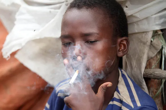 Abdulahi Yaroow, 13, smokes a cigarette while chewing khat at the same time in Mogadishu August 10, 2014. (Photo by Thomas Mukoya/Reuters)