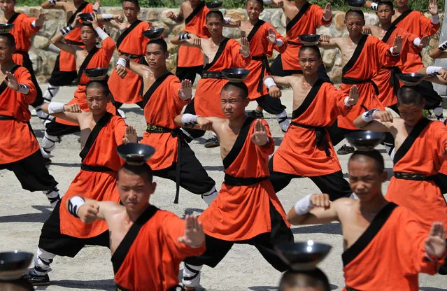 Martial students practise Shaolin Kong Fu with bowls filling with water on theirs heads at the square outside a science spot on July 28, 2016 in Zhengzhou, Henan Province of China. The students practise Shaolin Kong Fu in daytime, and some of them will perform in the Shaolin Zen Music Ritual at night in the science spot in Dengfeng, Zhengzhou city. (Photo by VCG/VCG via Getty Images)