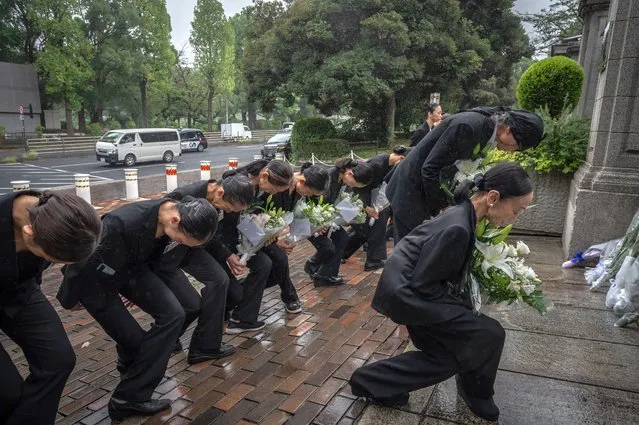 Members of a ballet company lay flowers outside the British embassy following the death of Queen Elizabeth II, in Tokyo on September 9, 2022. Queen Elizabeth II, the longest-serving monarch in British history and an icon instantly recognisable to billions of people around the world, died at her Scottish Highland retreat on September 8 at the age of 96. (Photo by Yuichi Yamazaki/AFP Photo)