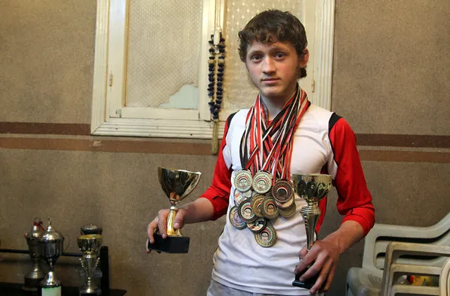 Gymnast Ahmad al-Sawas poses with his medals and trophies inside his home in the rebel-held Bustan al-Qasr neighbourhood of Aleppo, Syria March 23, 2016. (Photo by Abdalrhman Ismail/Reuters)
