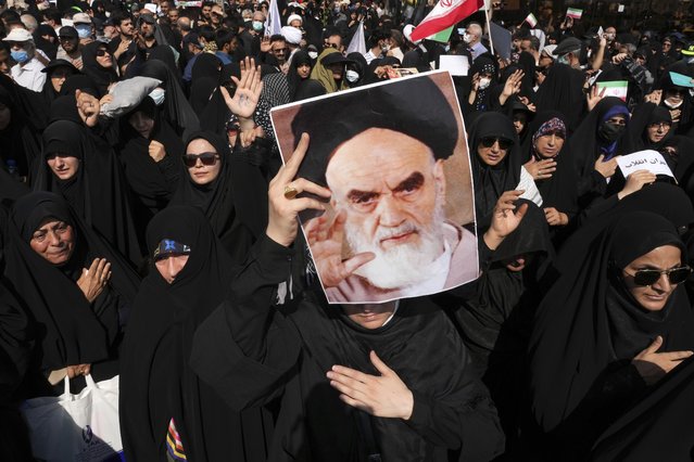 A pro-government demonstrator holds a poster of the late Iranian revolutionary founder Ayatollah Khomeini while attending a rally after the Friday prayers to condemn recent anti-government protests over the death of a young woman in police custody, in Tehran, Iran, Friday, September 23, 2022. The crisis unfolding in Iran began as a public outpouring over the the death of Mahsa Amini, a young woman from a northwestern Kurdish town who was arrested by the country's morality police in Tehran last week for allegedly violating its strictly-enforced dress code. (Photo by Vahid Salemi/AP Photo)