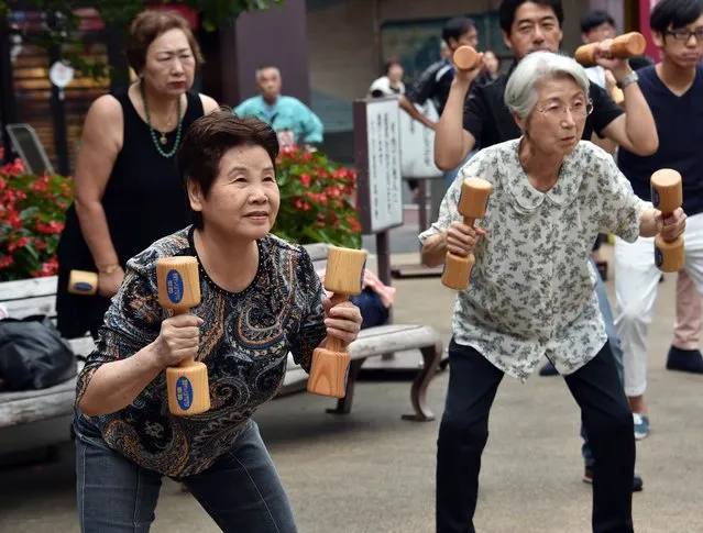 Elderly residents work out with wooden dumb-bells in the grounds of a temple in Tokyo on September 15, 2014 to celebrate Japan's Respect-for-the-Aged-Day. The number of people aged 65 or older in Japan is at a record 32.96 million, accounting for an all-time high of 25.9 percent of the nation's total population, the government announced. (Photo by Yoshikazu Tsuno/AFP Photo)