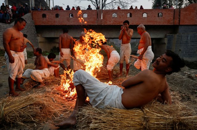 Devotees gather beside a fire before taking a holy bath at the Hanumante River during the final day of the month-long Swasthani Brata Katha festival in Bhaktapur, Nepal on February 12, 2025. (Photo by Navesh Chitrakar/Reuters)