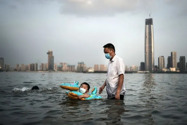 A boy wearing a face mask swims with a rubber ring in a flooded Jiangtan park caused by heavy rains along the Yangtze river on June 30, 2020 in Wuhan, China. Since June 13, 2020 the response level of public health emergencies in Hubei Province has been reduced to level 3. Wuhan's health commission said that the city had no asymptomatic cases as of June 15, and there are no more close contacts under medical observation. (Photo by Getty Images)