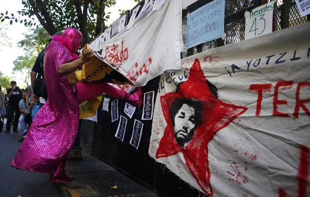 A man dressed as famous Mexican Lucha Libre wrestler El Santo kicks a police fence during a demonstration to demand information for the 43 missing students of the Ayotzinapa teachers' training college, outside Mexico's embassy in Buenos Aires October 22, 2014. The students went missing in Iguala, in the southwestern state of Guerrero on September 26 after clashing with police and masked men, and dozens of police have been arrested in connection with the case – which has sent shockwaves across Mexico. (Photo by Marcos Brindicci/Reuters)