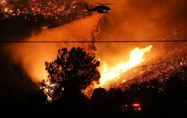 A firefighting helicopter performs a water drop over the Lake Fire on August 12, 2020 in Lake Hughes, California. The fire, which quickly grew to 10,000 acres, was burning in the Lake Hughes area of Angeles National Forest prompting mandatory evacuations and threatening around 100 structures. (Photo by Mario Tama/Getty Images)