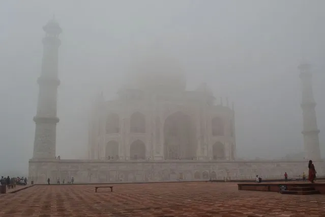 Tourists visit the Taj Mahal amid dense fog during the morning in Agra, India on October 12, 2022. (Photo by Pawan Sharma/AFP Photo)