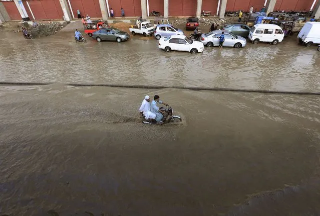 A motorcyclist drives through a flooded road after a heavy rainfall in Karachi, Pakistan, Monday, July 27, 2020. (Photo by Fareed Khan/AP Photo)