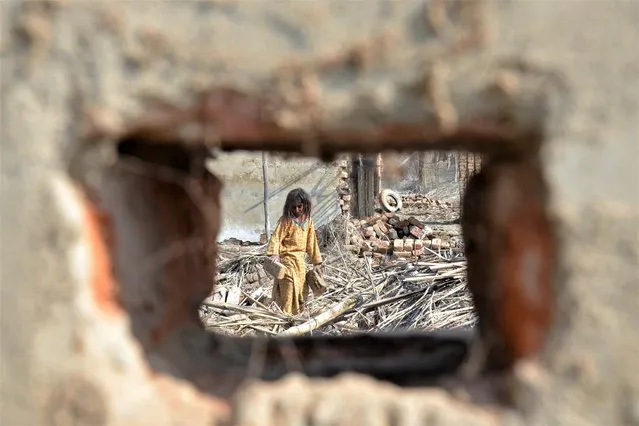 A flood-affected girl collects bricks from the debris of her damaged house in the flood-hit area of Dera Allah Yar in Jaffarabad district of Balochistan province on January 9, 2023. The UN chief called on January 9 for “massive investments” to help Pakistan recover from last year's devastating floods and better resist climate change, as financial pledges poured in. (Photo by Fida Hussain/AFP Photo)