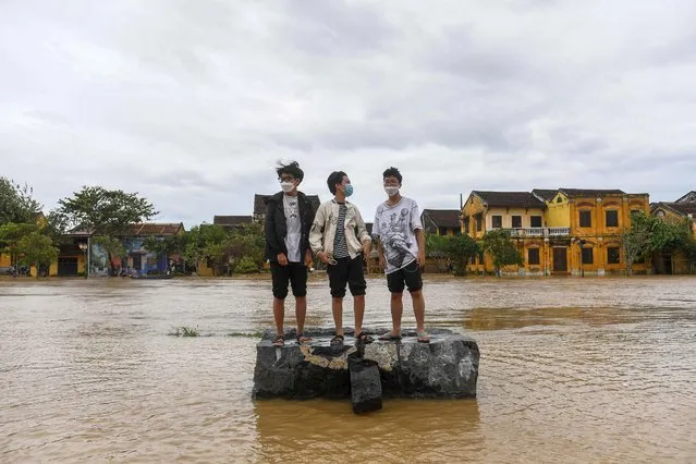 Boys stand on a rock on a flooded street after Typhoon Noru made landfall in Hoi An, Vietnam's Quang Nam Province on September 28, 2022. (Photo by Nhac Nguyen/AFP Photo)