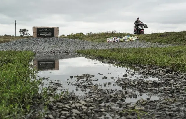A woman rides her motorbike past the crash site of the Malaysia Airlines Flight 17, near the village of Hrabove, eastern Ukraine, Wednesday, September 28, 2016. Dutch-led criminal investigators said Wednesday, they have solid evidence that a Malaysian jet was shot down by a Buk missile moved into eastern Ukraine from Russia. (Photo by Inna Varenytsia/AP Photo)