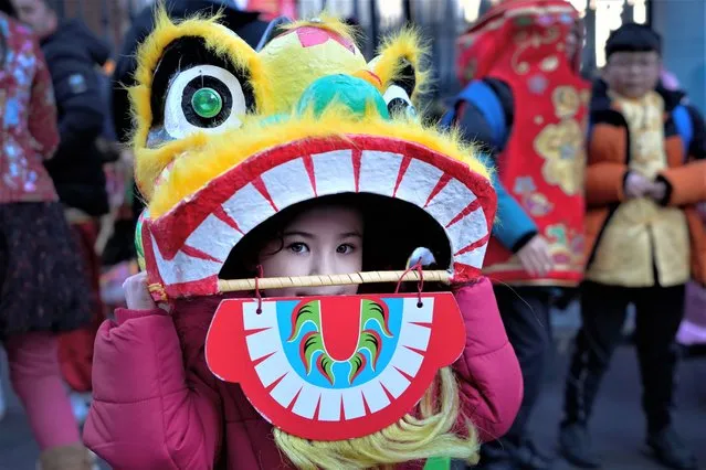 A young performer looks out of a dragon mask ahead of the Lunar New Year parade in London, Sunday, January 22, 2023. The parade is to mark the arrival of the Year of the Rabbit, with thousands of visitors expected to watch the spectacular show and Lion Dances in the capital. (Photo by Kirsty Wigglesworth/AP Photo)