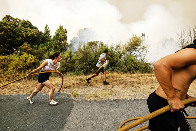 Local residents and volunteers work together to put out an encroaching wildfire in Larouco, northwestern Spain, Wednesday, August 13, 2025. (Photo by Lalo R. Villar/AP Photo)