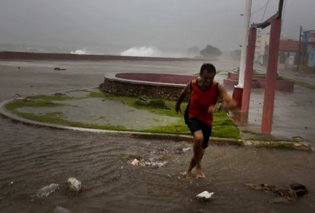 A man runs from a wave at the waterfront  in Baracoa, Cuba, Tuesday, October 4, 2016. The dangerous Category 4 storm blew ashore around dawn in Haiti. It unloaded heavy rain as it swirled on toward a lightly populated part of Cuba and the Bahamas. (Photo by Ramon Espinosa/AP Photo)