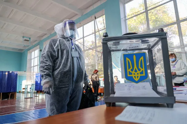 A member of an electoral commission wearing personal protection equipment stands next to a ballot box at a polling station during local elections amid the coronavirus disease (COVID-19) outbreak in Sloviansk, Ukraine on October 25, 2020. (Photo by Stanislav Kozliuk/Reuters)