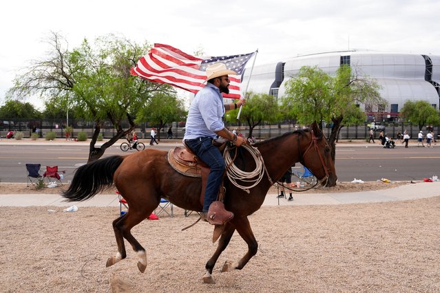 A man holding a U.S. flag rides a horse outside State Farm Stadium, on the day of a memorial service for slain conservative commentator Charlie Kirk, in Glendale, Arizona, U.S., September 21, 2025. (Photo by Cheney Orr/Reuters)