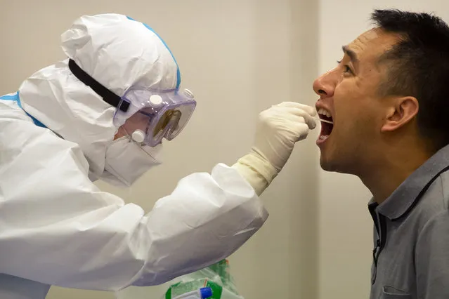 A worker in a protective suit takes a throat swab for a COVID-19 test in Wenchang in southern China's Hainan Province, Sunday, November 22, 2020. Authorities are conducting mass testing and shutting down schools after China reported three new domestically transmitted cases in the past 24 hours – two in northern Inner Mongolia province and one in Shanghai. (Photo by Mark Schiefelbein/AP Photo)