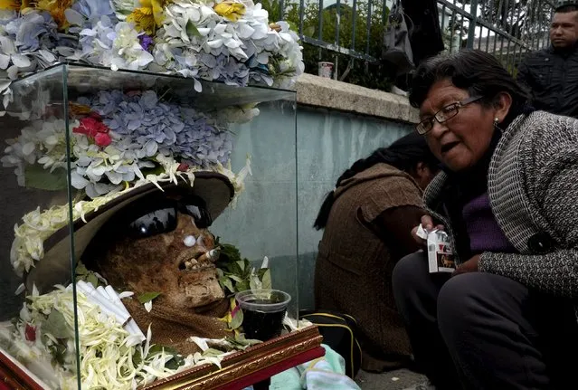 A devotee sits near skulls placed on the floor during a ceremony held for the "Dia de las natitas" (Day of the Skull) celebrations at the General Cemetery of La Paz, November 8, 2015. (Photo by David Mercado/Reuters)