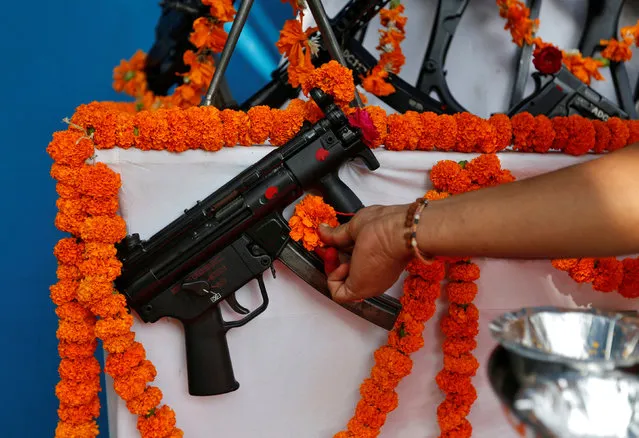 A Hindu priest offers prayers to a weapon as part of a ritual at the police headquarters on the occasion of Vijaya Dashmi or Dussehra festival in Ahmedabad, India October 11, 2016. (Photo by Amit Dave/Reuters)
