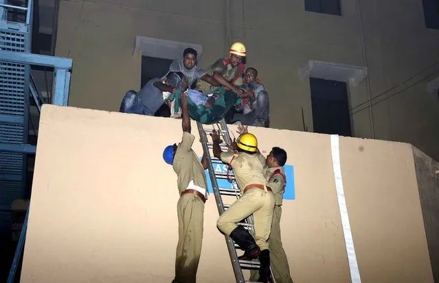 This photograph taken on October 17, shows Indian rescue workers lowering a body of a victim of a massive fire at the SUM hospital building in Bhubaneswar, the capital of coastal Odisha state At least 19 people were killed Monday when a fire broke out at a leading private hospital in an eastern Indian city, police said, with officials warning the death toll could rise. (Photo by AFP Photo)