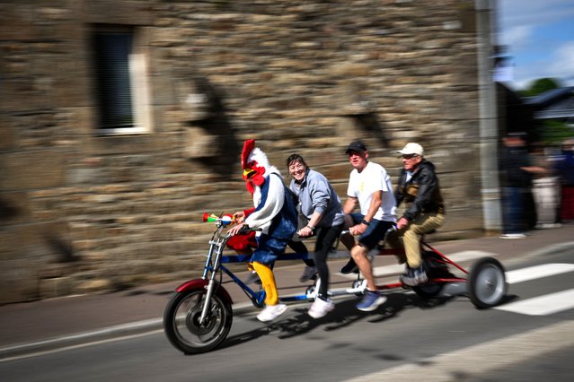 A supporter dressed like a rooster rides with friends on the sidelines of the Elit road women French championships cycling race, in Saint-Martin-de-Landelles, western France, on June 22, 2024. (Photo by Loic Venance/AFP Photo)