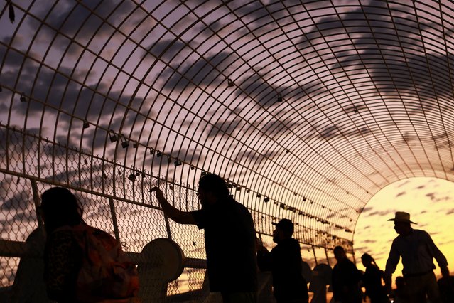 People stand near padlocks with messages of gratitude hanging on a pedestrian bridge near the U.S. Consulate General, where people use the bridge as a place to express thanks after obtaining approval for their migration documents, in Ciudad Juarez, Mexico, on October 6, 2025. (Photo by Jose Luis Gonzalez/Reuters)