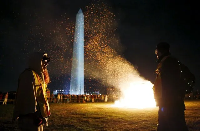 Fire safety workers keep back a crowd of spectators and participants as an interactive art installation by artist Michael Verdon called the “Temple of Essence” dedicated to "victims of the war on drugs" is burned on the U.S. National Mall in front of the Washington Monument (rear) in Washington November 22, 2015.  (Photo by Jim Bourg/Reuters)