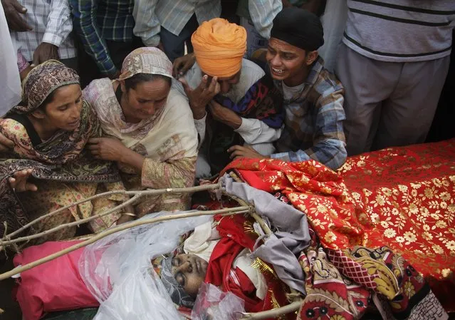 Relatives grieve near the body of Indian woman Rajinder Kaur, who was killed in Pakistani shelling during her funeral at Khour village in Ramgarh sector, Samba district of Jammu and Kashmir, India, Tuesday, November 1, 2016. (Photo by Channi Anand/AP Photo)