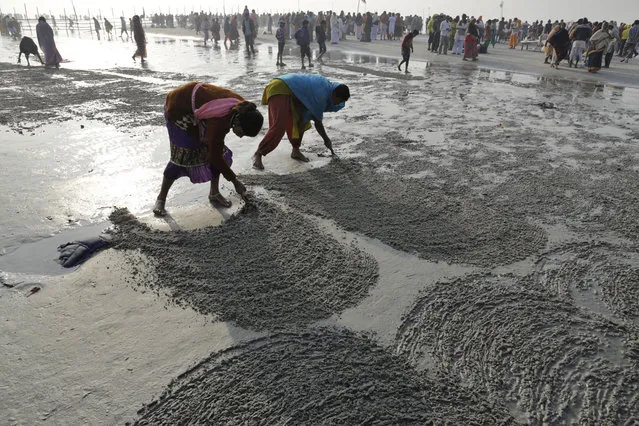 Local women scratch the surface of the beach to find coins thrown by pilgrims as offerings at Gangasagar, India, Thursday, January 15, 2015. The annual holy dip, that devotees believe absolves them of sin, was held Jan. 14-15 at the confluence of the Bay of Bengal and Ganges River. (Photo by Bikas Das/AP Photo)