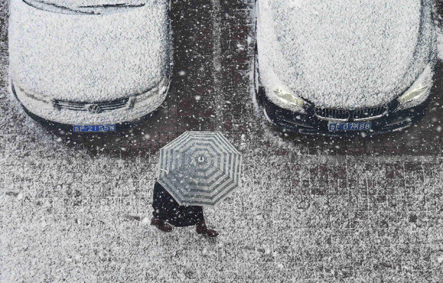 A resident walks with an umbrella during a snowfall in Yantai in China' s eastern Shandong province on December 4, 2017. An orange alert of road icing was issued by local meteorological bureau on December 4. (Photo by AFP Photo/Stringer)