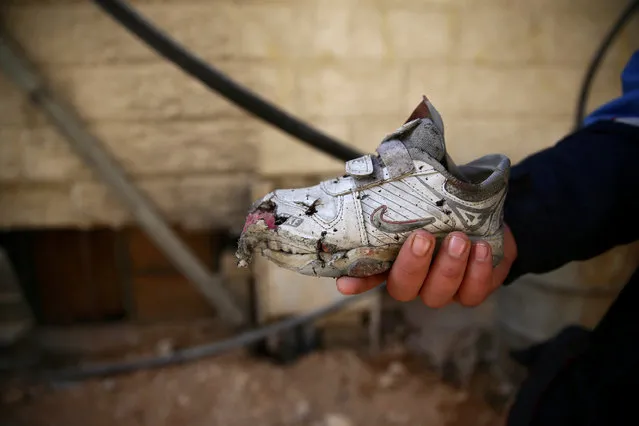 A man shows a damaged shoe of a child, after an air strike on a kindergarten in the rebel-held besieged city of Harasta, in the eastern Damascus suburb of Ghouta, Syria November 6, 2016. (Photo by Bassam Khabieh/Reuters)