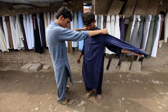 A Pakistani tries second-hand clothes in preparation for Eid al-Fitr, when traditionally Muslims buy clothes for the celebrations which mark the end of the Muslim holy month of Ramadan, in Peshawar, Pakistan, 13 June 2018. Eid al-Fitr is an important religious holiday celebrated by Muslims worldwide that marks the end of Ramadan, the Islamic holy month of fasting including praying during the night time and abstaining from eating, drinking, and sexual acts daily between sunrise and sunset. Ramadan is the ninth month in the Islamic calendar and it is believed that the Koran's first verse was revealed during its last 10 nights. (Photo by Bilawal Arbab/EPA/EFE/Rex Features/Shutterstock)